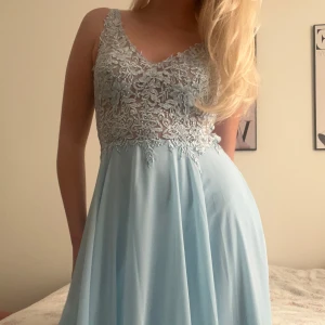 Ljusblå klänning med spetsdetaljer - ljusblå balklänning från JJ house med spetsöverdel och öppen rygg. Klänningen är helt oanvänd och prislappen sitter kvar. Jag är 170 och klänningen går ner till marken💞 pris går att diskuteras