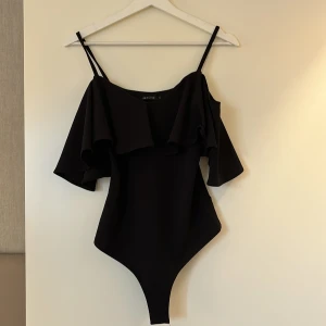 Off shoulder body - Säljer en svart off shoulder body med volang runt hela. Väldigt fint skick, lite tjockare material så volangerna lägger sig väldigt fint 