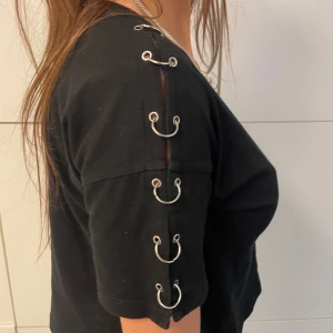 SVART T-SHIRT MED RINGAR - Coolaste svarta tishan med ringar längs ena ärmen. Skönt material och bra passform!! Tjejen på bilderna är 175 cm lång och t-shortsen är i storlek S. Hör av er vid frågor!! 