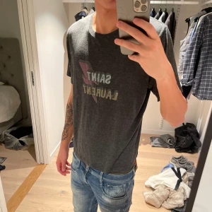 Saint Laurent T-shirt  - Grå snygg saint Laurent T-shirt med tryck, jag är 187 och väger 65kg.
