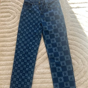 Blå jeans med stjärnmönster från Jaded London - Snygga blå jeans från Laced med ett unikt rutigt mönster och stjärnor. De har en klassisk femficksdesign och knappgylf. Perfekta för att sticka ut med en cool stil.