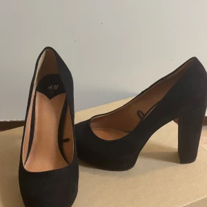 Svarta pumps från H&M - Eleganta svarta pumps från H&M med hög klack och rundad tå. Perfekta för en stilren look.