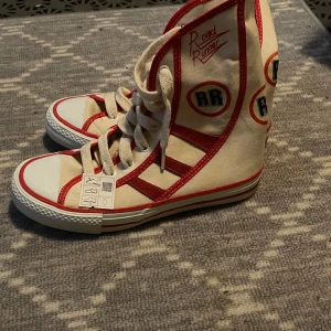 Road Runner sneakers med röd detalj - Unika Road Runner sneakers i beige med röda detaljer och RR-logga. Skorna har snörning och en cool retrodesign. Perfekta för dig som vill sticka ut!