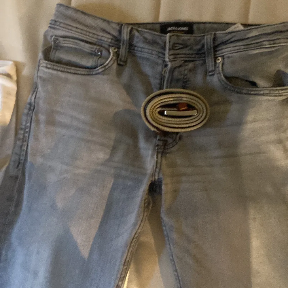 Säljer ett par snygga grå jeans från Jack & Jones. De har en klassisk femficksdesign och är i väldigt bra skick. Perfekta för både vardag och fest! Passformen är straight och de har en knappgylf. Bälte ingår för 100kr extra.. Farkut & Housut.