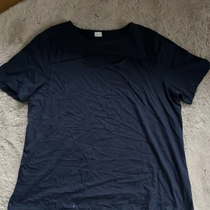 Mörkblå t-shirt - Säljer en enkel och stilren mörkblå t-shirt. Perfekt för vardagsbruk med en normal passform och korta ärmar. Skön och lätt att matcha med olika outfits.och ett hål vid bysten.