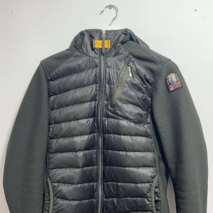 Parajumpers Cardigan - Snygg grön jacka från Parajumpers med quiltad design och dragkedja. Jackan har en huva och en bröstficka med dragkedja. Perfekt för kyligare dagar med sin stilrena look och praktiska detaljer.