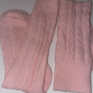 Rosa stickade strumpor - Säljer ett par supermysiga rosa stickade strumpor. De har ett fint flätmönster och är perfekta för att hålla fötterna varma under kalla dagar. Strumporna är  nya endast öppnade och har en mjuk och bekväm passform. Perfekta för mysiga hemmakvällar eller som en söt accessoar till din outfit! 💖