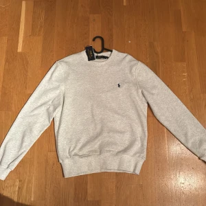 Grå tröja från Ralph Lauren - Säljer en stilren grå tröja från Ralph Lauren i nytt skick.  Size -S/M,  Ny med tags , skriv vid frågor , sitter lite större i sizen