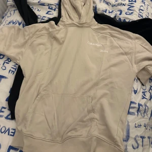 Beige hoodie från Calvin Klein - Säljer en snygg beige hoodie från Calvin Klein Jeans. Den har en klassisk design med känguruficka och Calvin Klein-logga på bröstet. Perfekt för en avslappnad stil och passar till alla tillfällen. Superbekväm och stilren!