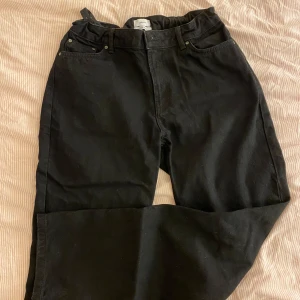 Svarta jeansbyxor från Grunt - Säljer ett par svarta jeansbyxor från Grunt i bra skick. De har en klassisk femficksdesign med knappar och dragkedja framtill. Perfekta för både vardag och fest! Det är en avslappnad passform och går att justera i midjan. 29 i storlek motsvarar 176cm i längd.  