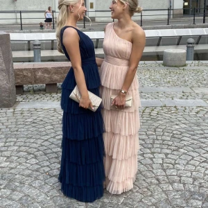 Balklänning - (Säljer åt min syster) Jättefin mörkblå balklänning med volanger och oneshoulder-design. Storlek 36, men passar både stl. 34-36 Klänningen är klippt nedtill av en sömmerska och passar min syster som är 163 cm lång. Har endast använts 1 gång under balen och är i fint skick. Säljer för 1100 kr💕