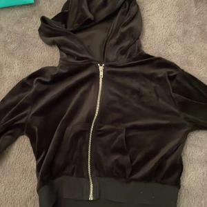 Svart hoodie från H&M - Säljer en svart hoodie från H&M i storlek XS. Den har en dragkedja framtill och är gjord i ett mjukt, glansigt material som liknar sammet. Perfekt för en avslappnad stil eller mysiga dagar hemma. 🖤