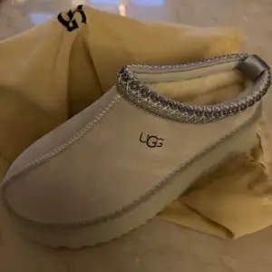 Säljer ett par snygga och bekväma UGG skor i beige färg. De har en mjuk insida och en robust sula som ger bra stöd. Perfekta för kalla dagar när du vill hålla fötterna varma och mysiga. Skorna är i nytt skick och kommer med originalpåse.