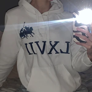 Vit hoodie med blå och röda detaljer - Säljer en vit hoodie med blått tryck på framsidan och rött nummer på ärmen. 