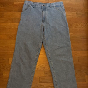 Ljusa jeansbyxor från Carhartt - Säljer ett par ljusa jeansbyxor från Carhartt i bra skick. De har en straight passform och flera praktiska fickor. Storlek 32x34