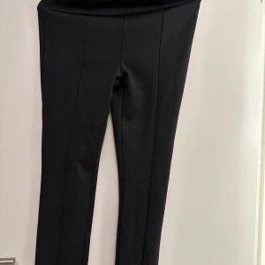 Svarta byxor med slits från Zara - Snygga svarta leggings från Zara med hög midja och stilrena sömmar. Leggings har en diskret slits vid anklarna som ger en modern touch. Str m snygga i passformen 
