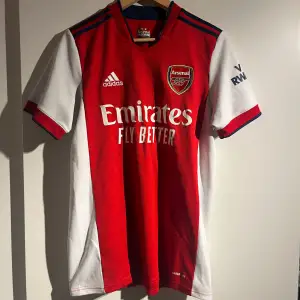 Säljer en snygg röd Arsenal fotbollströja från Adidas. Perfekt för alla Arsenal-fans! ⚽️