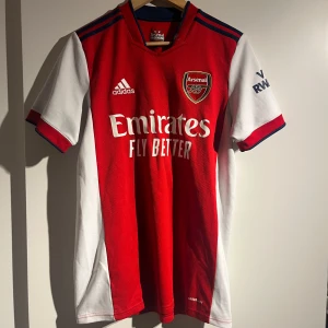 Röd Arsenal fotbollströja från Adidas - Säljer en snygg röd Arsenal fotbollströja från Adidas. Perfekt för alla Arsenal-fans! ⚽️