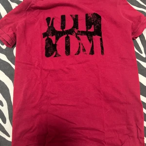 Röd t-shirt från Volcom - Säljer en cool röd t-shirt från Volcom i bomull. Den har ett svart tryck på framsidan och en liten logga på ärmen. Perfekt för vardagsbruk eller en avslappnad fest. Skön och stilren design!
