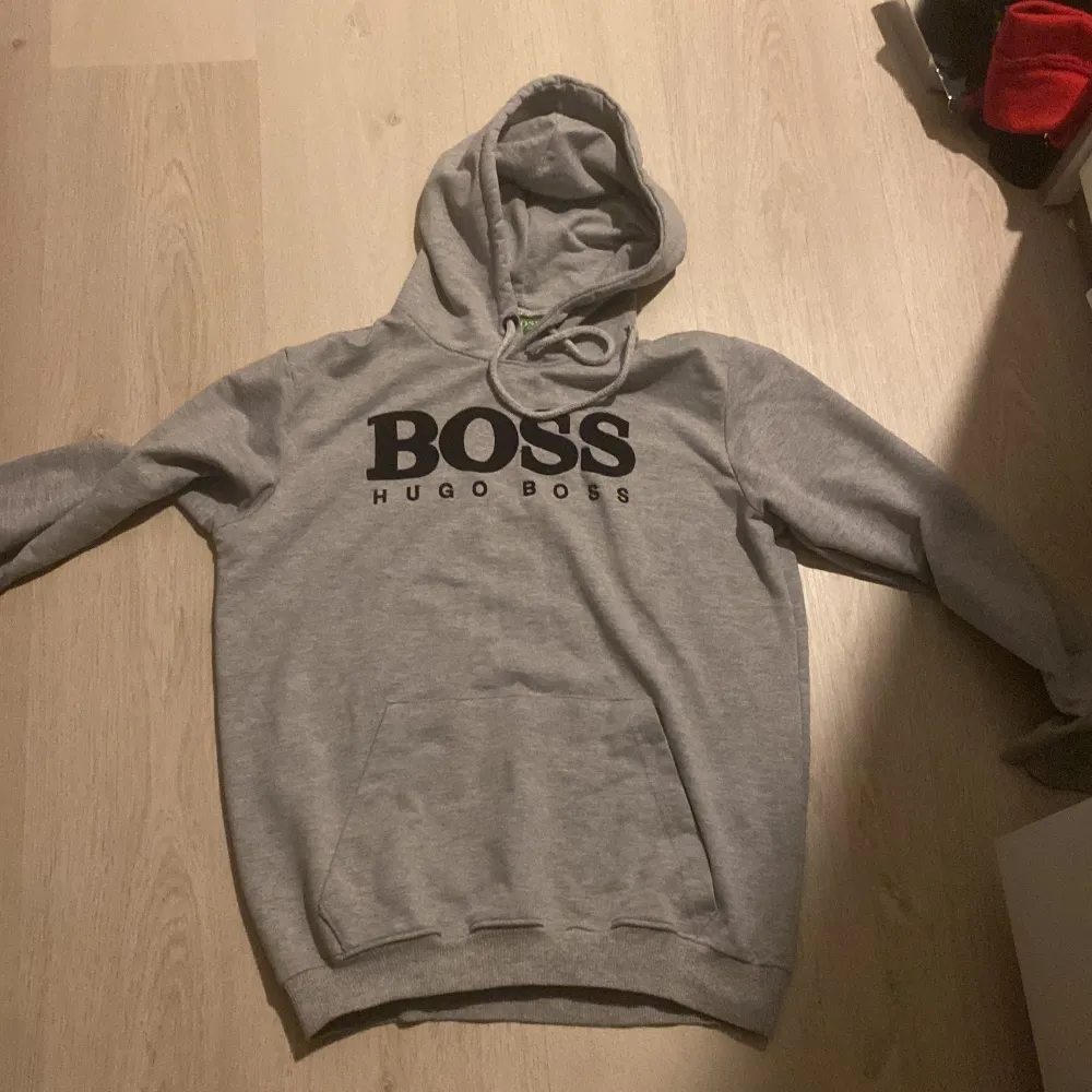 Säljer en snygg grå hoodie från Hugo Boss i mycket bra skick. Den har en stor BOSS-logga på bröstet och en praktisk magficka. Perfekt för både vardag och chill. Huvan har passform. Passar perfekt till höst och vår!. Neuletakit & Villapaidat.