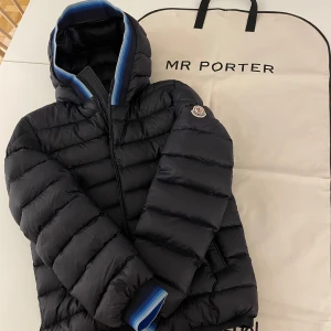 Moncler Jacka - Moncler Avrieux Stripe-Trimmed Quilted Shell Hooded Down Jacket.  Marinblå Moncler jacka storlek 1, sitter som S/M. Knappt använd, därav nyskick.  Köpt på MR PORTER, orginal kvitto finns. Även dustbag från MR.Porter medföljer