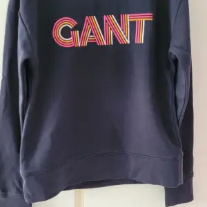 Säljer en snygg mörkblå sweatshirt från GANT i mycket bra skick. Den har ett färgglatt GANT-tryck på bröstet i rött, gult och rosa. Perfekt för en avslappnad stil under höst och vår. Passar både till jeans och kjol!