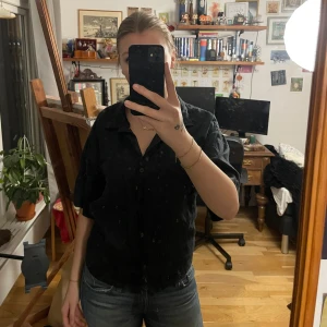 Svart linneskjorta - Säljer en svart kortärmad skjorta i linne. Den har en klassisk krage och knappar framtill. Perfekt för  sommar. Skjortan är i bra skick och passar både till vardags och fest. Bara använd fåtal gånger 