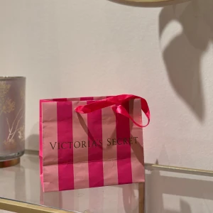  shoppingväska från Victoria's Secret - Snygg och praktisk rosa randig shoppingväska från Victoria's Secret. Perfekt för en shoppingtur eller som presentpåse, även som dekoration 🩷.
