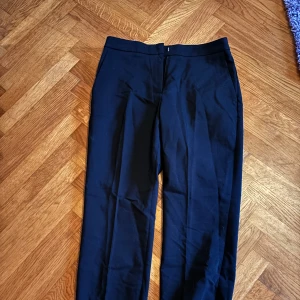 Svarta kostymbyxor - Snygga svarta kostymbyxor i mycket bra skick. De har en klassisk straight passform och är perfekta för både kontoret och festliga tillfällen. Byxorna är gjorda i ett bekvämt material som ger en stilren look. Perfekta för höst och vinter!