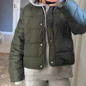 Grön pufferjacka - Säljer en snygg grön pufferjacka i mycket bra skick. Den har en cool, quiltad design med knappar framtill. Perfekt för höst och vår när du vill hålla dig varm men ändå se stilren ut. Jackan har långa ärmar och en normal passform. Passar perfekt till både vardag och lite mer avslappnade tillfällen.