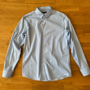 J.Lindeberg kostymskjorta ljusblå L - Fin skjorta i mycket bra skick, använd fåtal gånger. Nypris >1000kr Vid några funderingar är det bara att höra av sig!