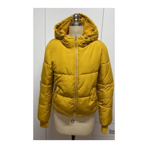 Gul pufferjacka med huva - Säljer en superfin gul pufferjacka med huva. Den har en dragkedja framtill och är perfekt för kyliga dagar. Jackan är i mycket bra skick och har långa ärmar. Den är både snygg och praktisk för höst och vinter.