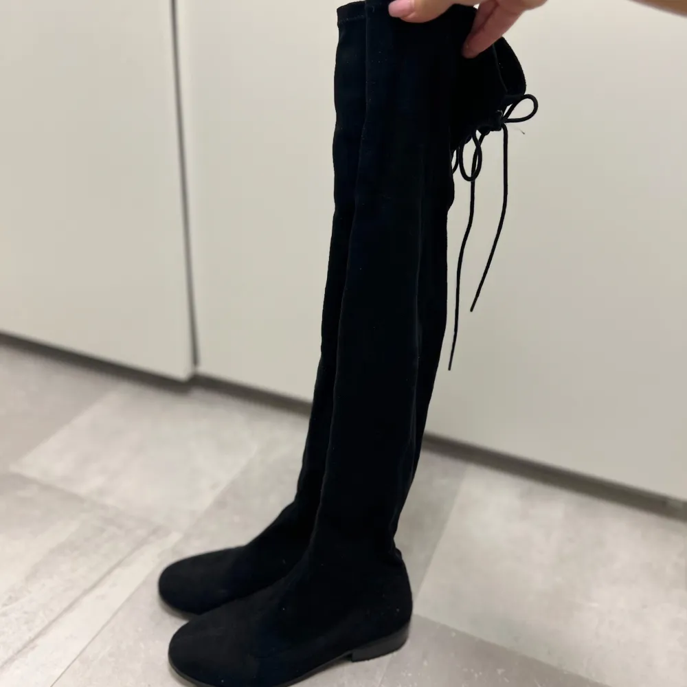 Säljer ett par snygga svarta overknee boots i mjuk mocka. De har en tight passform och knytning baktill för justerbarhet. Perfekta för höst och vinter, och de ger en stilren look till vilken outfit som helst. Använda ett fåtal gånger och är i topp skick. Storlek 37, pris 400kr. Skor.