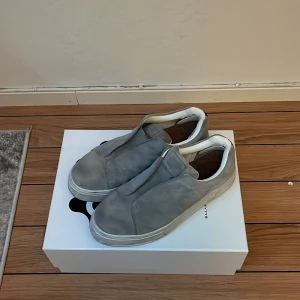 Eytys Doja - Säljer ett par stilrena grå sneakers från Eytys i mycket bra skick. Skorna är i mocka och har en chunky vit sula som ger en modern look. Perfekta för både vardag och fest. De har en enkel slip-on design utan snörning, vilket gör dem superbekväma att ta på och av. Passar perfekt till både jeans och mer dressade outfits. Använda en gång, var för stora för mig. Dem är i strl 45, men passar 44 bäst enligt mig. Köpta för 2200kr så anser 1800kr som prisvärt. Pris går att diskuteras