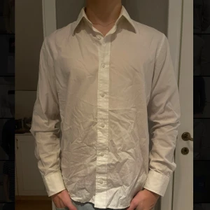 Vit skjorta från Tiger of Sweden ⭐️ - Säljer en stilren vit skjorta från Tiger of Sweden i storlek 41. Skjortan är långärmad och har klassiska knappar framtill. Perfekt för både formella och avslappnade tillfällen. Materialet känns mjukt och bekvämt. ✅ Ostrykt på bilden, använd ett par gånger. Org pris: ca 1200kr