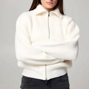 Vit stickad tröja med dragkedja - Säljer en supermysig vit kofta med dragkedja framtill. Den är ribbad och har en hög krage. Passar till allt och är i mycket bra skick. Ordinarie pris 399kr 