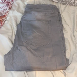 Grå byxor från H&M Divided - Säljer ett par grå byxor från H&M Divided i storlek 44. De har en klassisk design med fem fickor och en knappgylf. Perfekta för vardagsbruk eller en avslappnad dag ute. Passar bra till både sneakers och boots.