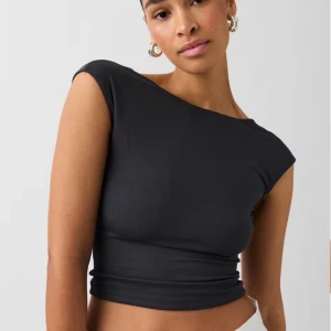 Svart oneshoulder topp - Snygg svart oneshoulder topp som är perfekt för en utekväll. Den har en tight passform och är tillverkad i ett mjukt och stretchigt material. Toppen är ärmlös och har en öppen rygg som ger en elegant touch. Den är aldrig använd.