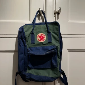 Blå och grön ryggsäck från Fjällräven - Säljer en klassisk Fjällräven Kånken ”Save the artic fox” ryggsäck i blått och grönt. Den är i bra skick.