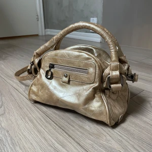 Handväska - Gullig handväska som har en del defekter (se bilderna) men som ändå går utmärkt att använda och är så fin! Axelbandet går att ta av. Har fått så många komplimanger för denna fina väska!