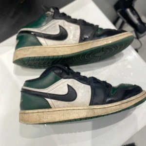 Jordan 1 green Toe low - Säljer ett par Nike Air Jordans i grönt och svart. Skorna har en cool vintage look med gröna sulor och svarta detaljer. De har snörning och den klassiska Air Jordan-loggan på hälen. Perfekta för dig som vill ha en unik stil! 🏀