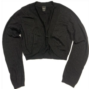 Glittrig croppad figursydd bolero kofta - Figursytt kroppsnära kofta från märket Esprit  Storlek L - sitter som en M  Svart glittrigt tyg, sticker inte  Går att fästa i mitten med en knapp Köpt på second hand butik, väldigt fint skick inga revor eller synliga defekter 