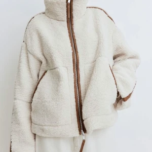 Ny teddyjacka pilejacka storlek M från HM - Ny med tags. Vit med bruna läderimiterade detaljer. En tjock och varm teddyjacka i mjuk pile med kantband i ytbehandlad kvalitet. Jackan har lös passform, ståkrage, tvåvägsdragkedja fram och kängurufickor. Fodrad. Cremevit. H&M Storlek: M