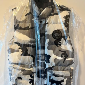 Artic camo väst från Canada Goose (BLACK LABEL) - Säljer en snygg och varm dunväst från Canada Goose i artic camouflage. Västen är black label och utgått i Canada goose sortimentet. Perfekt för höst och vinter när du vill hålla stilen och värmen. Pris går att diskuteras 