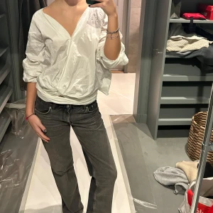 Vit omlottblus - Säljer en stilren vit omlottblus med knytband i midjan. Blusen har en v-ringad design och trekvartsärmar, vilket ger en avslappnad men chic look. Perfekt för att lyfta vilken outfit som helst! Man kan knyta den som man vill
