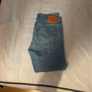 Levis 512 jeans i ljusblå denim - Säljer ett par klassiska Levis 512 jeans i ljusblå denim. De har en straight passform och är perfekta för en avslappnad stil. Jeansens ikoniska läderpatch och röda etikett ger en tidlös look.