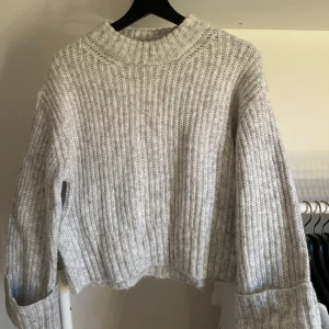 Grå stickad tröja - Grå stickad tröja med uppvikta ärmar. Aldrig använd och prislappen är kvar.