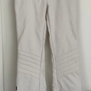 Vita skidbyxor från 8848 Altitude - Snygga vita damskidbyxor från 8848 Altitude med svarta dragkedjor och detaljer i superstrechigt material som gör att de formar sig efter kroppen. De har elastiska snölås och dragkedjor vid bensluten för justerbar passform. Jag har strl M i vanliga fall och dessa passar mig perfekt.