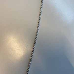 Silverfärgat armband med tvinnad design - Snyggt silverfärgat armband med en elegant tvinnad design. Perfekt för att ge en stilren touch till din outfit. Armbandet har en säker låsmekanism som gör det enkelt att ta på och av.