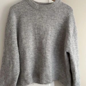 Grå stickad tröja från Gina Tricot - Mysig grå stickad tröja från Gina Tricot i premiumkvalitet. Tröjan har en klassisk rund hals och långa ärmar med ribbade muddar vid ärmslut och nederkant. Perfekt för kyliga dagar! ( EGNA BILDER PRIVAT)